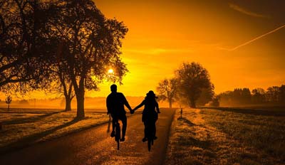 A silhouette of a couple biking towards the sunset in Medellin Colombia.